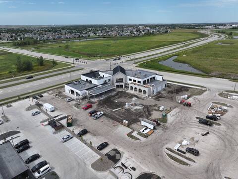 Aerial view across the new parking field toward Kettlestone Social, with the stormwater pond in the foreground