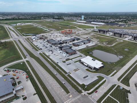 High wide aerial view over Kettlestone Central in Waukee, Iowa, looking back toward the city