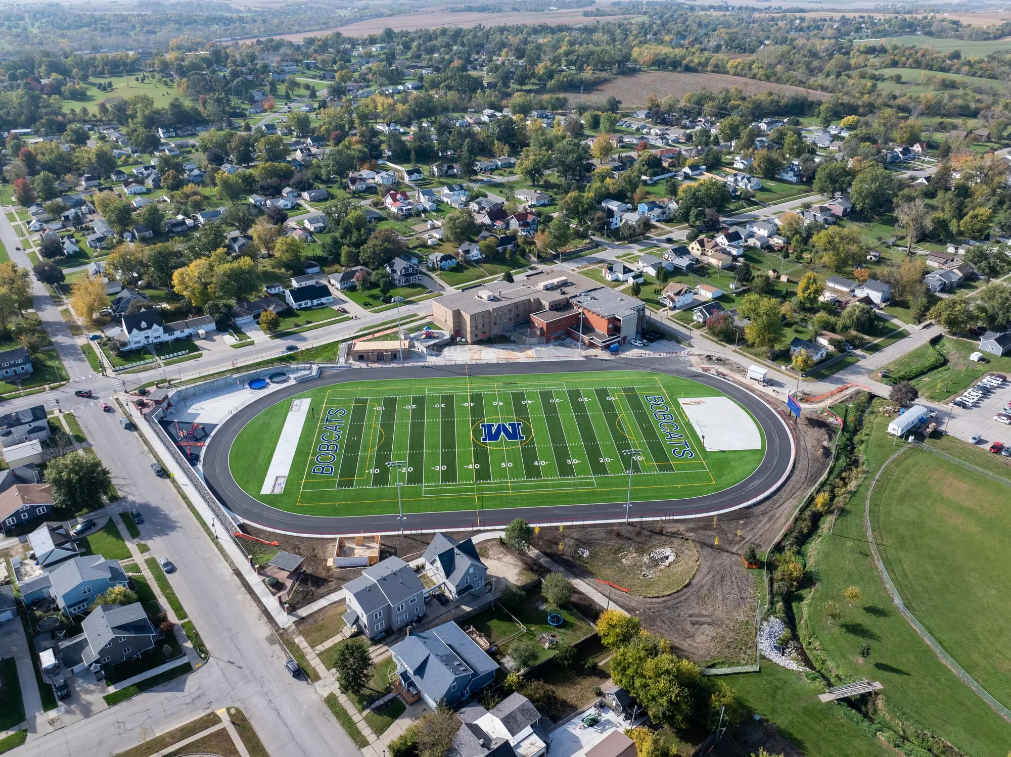 Completed Franklin Field in Marshalltown, Iowa &mdash; new turf, track and lighting seen from the air in October 2025, with the surrounding neighborhood and school