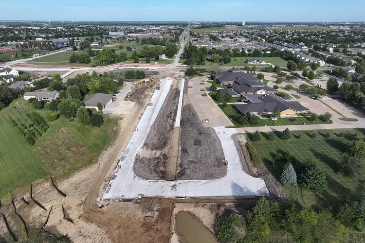 Aerial view of the University Avenue Extension in Waukee: fresh concrete paving on the new alignment leading into the existing road